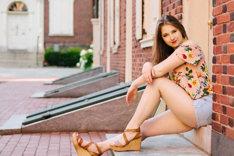 Girl sitting infront of an old building in old city Philadelphia posing for senior photography