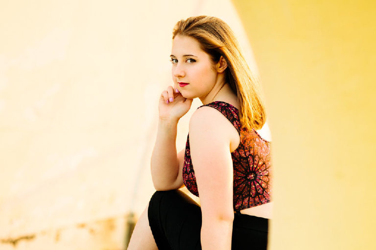 Girl looking back and posing with hand on face for senior photography at the navy shipyard in Philadelphia