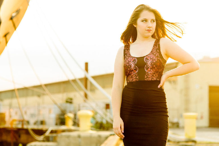 Clara striking a powerful pose at the navy shipyard posing for senior portraits for Kasey Ivan Photography in Philadelphia