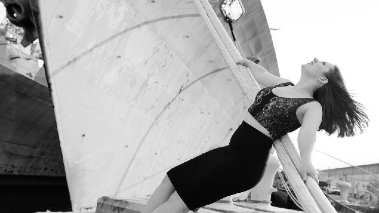 Senior girl leaning back on rope laughing at the navy shipyard in Philadelphia posing for a photographer