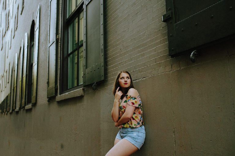 Senior girl leaning against a wall in an allyway in old city philadelphia