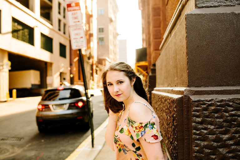 Senior girl standing on the sidewalk of philadelphia waiting to cross the street