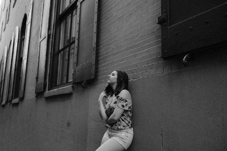 Senior girl playing with hair and thinking in an allyway in old city Philadelphia