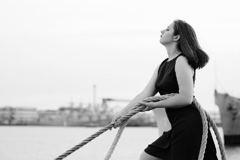 black and white photograph on a senior girl pulling on a rope with confidence and a powerful pose for Kasey Ivan Photography
