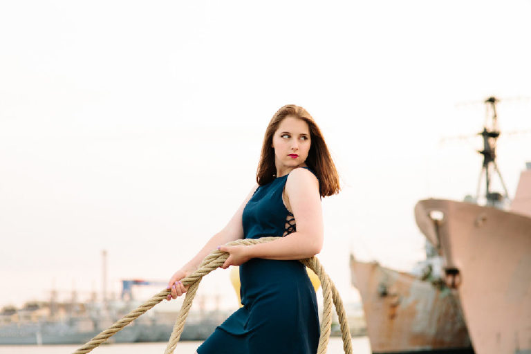 Senior girl looking back and pulling a on a rope in the navy shipyard in philadelphia posing strongly for Kasey Ivan Photography