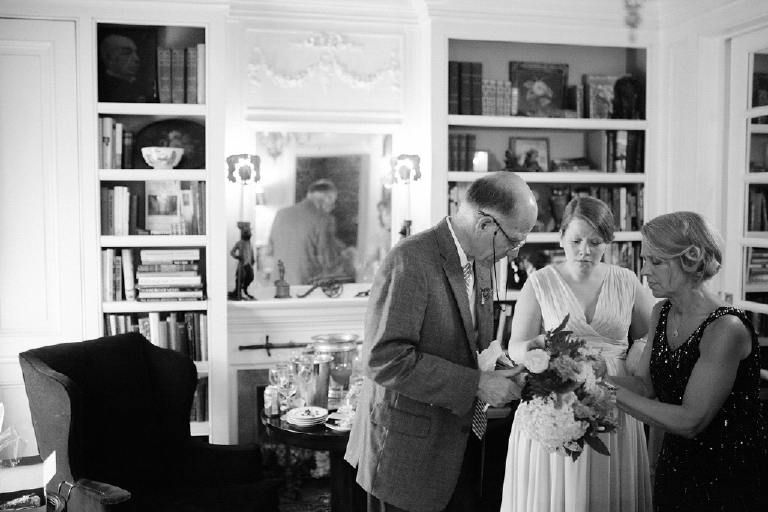 Black and white picture of a mom and dad helping their daughter get ready on her wedding day in the Porches on the Towpath in New Hope