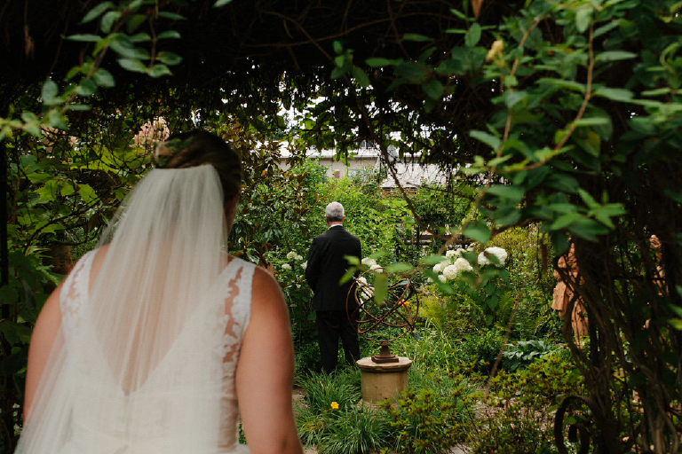 Bride walking to her groom in a garden for their first look in the Porches on the Towpath