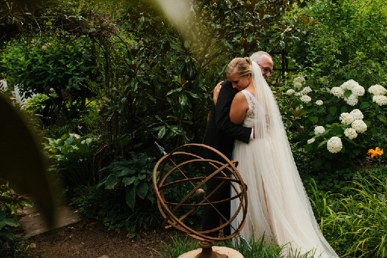 Future husband and wife embracing in a colorful garden with statues and flowers in the porches on the towpath in New Hope and Lambertville wedding photography by Kasey Ivan 