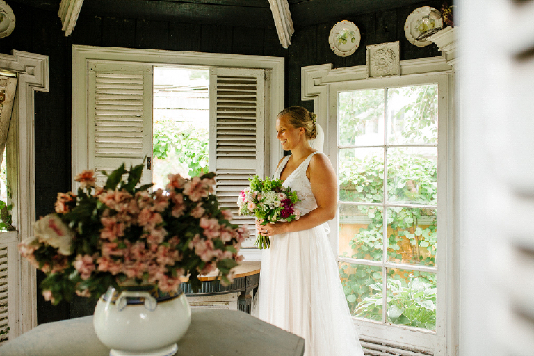 Bride standing in rustic chic room holding her bouquet of colorful flowers at the Porches on the Towpath in New Hope and Lambertville
