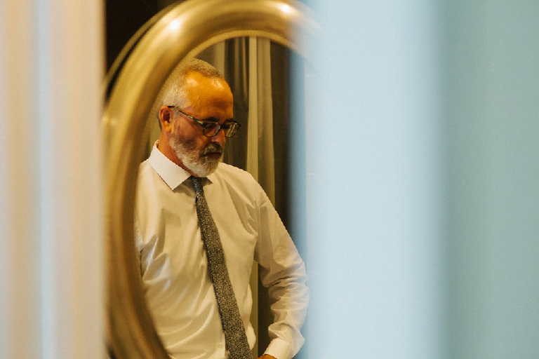 Picture of a groom in a mirror getting dressed for his wedding in New Hope