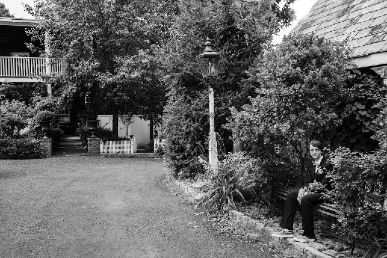 Black and white photo of bride and grooms daughter sitting on a bench in a garden in the Porches on the Towpath in New Hope and Lambertville