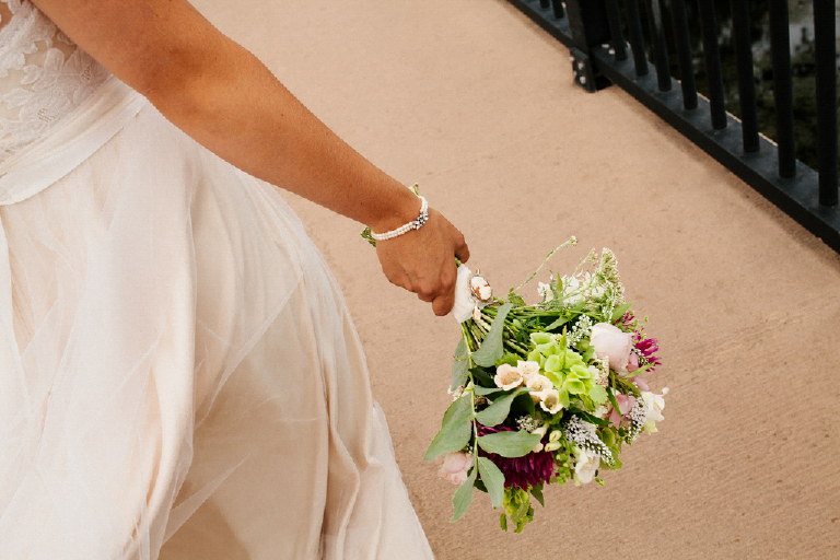 Bride holding her bouquet of flowers walking across the New Hope and Lambertville bridge
