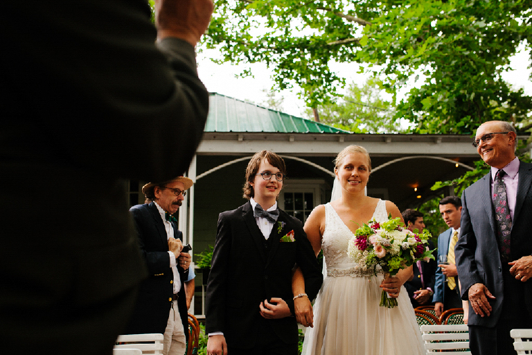 Bride walking down the aisle holding her bouquet of red and white flowers with her daughter Hamilton's Grillroom Lambertville New Hope