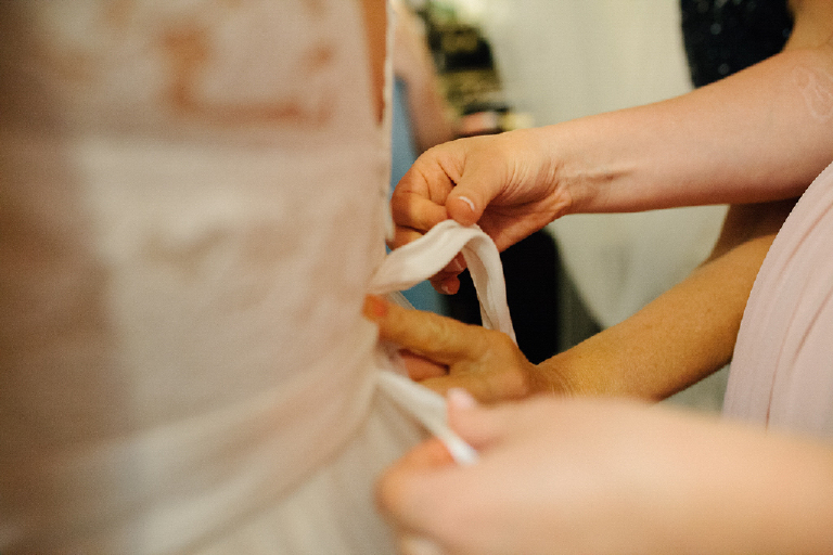 Picture of a mother tying the back of her daughters wedding dress getting ready for a chic wedding at porched on the towpath in lambertville New Hope 