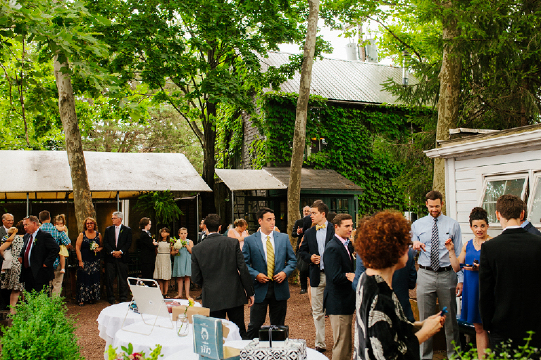 Wedding guests standing ion rstic padio surrounded by greenery