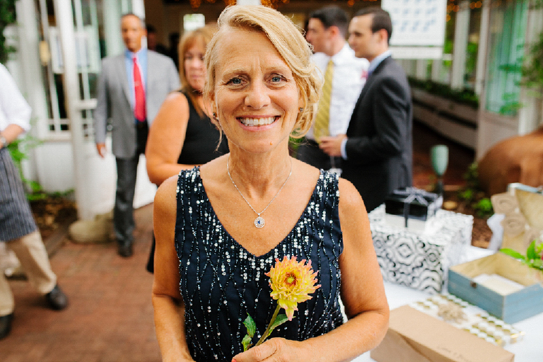Photography of a the mother of the bride at a wedding holding a colorful flower at Hamilton's Grillroom Lambertville New Hope