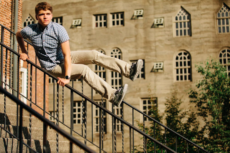 Tyler McClellan jumps over railing and stairs in blue shirt at the Mercer Museum in Doylestown Pennsylvania by photographer Kasey Ivan Photography