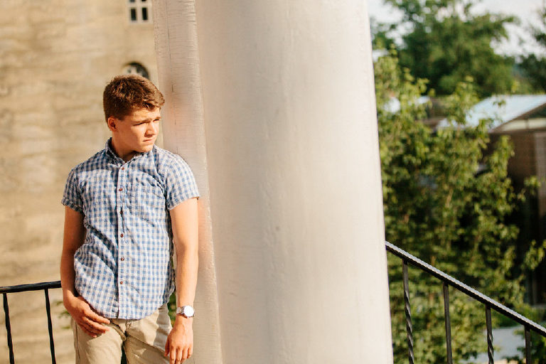 high school senior boy leans against pillars for senior pictures in Bucks County Pennsylvania by Kasey Ivan Photography