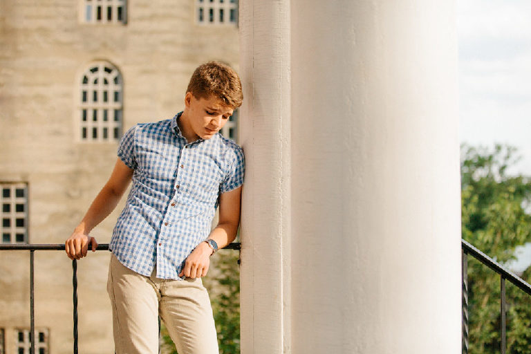 high school senior boy leans against pillars for senior pictures in Bucks County Pennsylvania by Kasey Ivan Photography