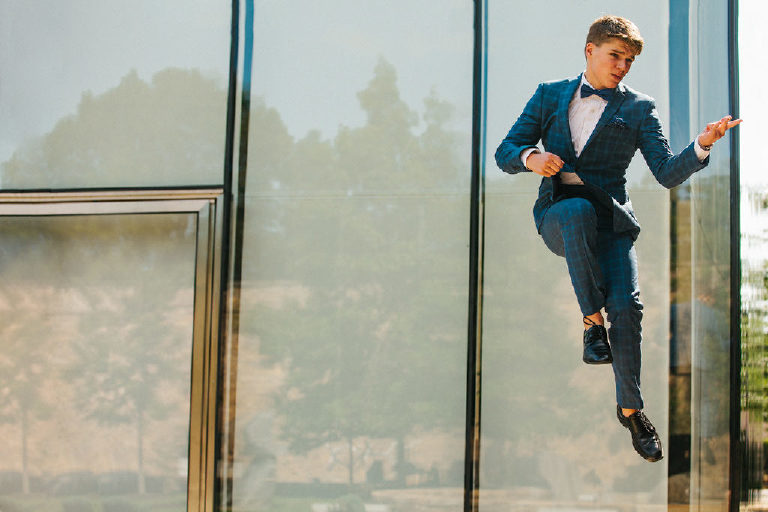 Tyler McClellan local high school senior jumps in the air and for rock and roll inspired GQ photo shoot of senior pictures outside Doylestown Michener Museum by photographer Kasey Ivan