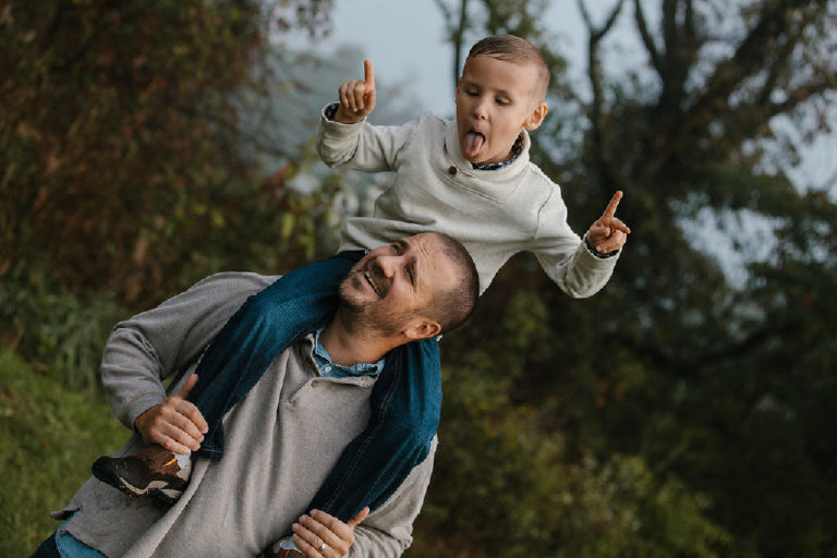 boy riding on fathers shoulders and making silly face for family portrait by New Hope photographer Kasey Ivan