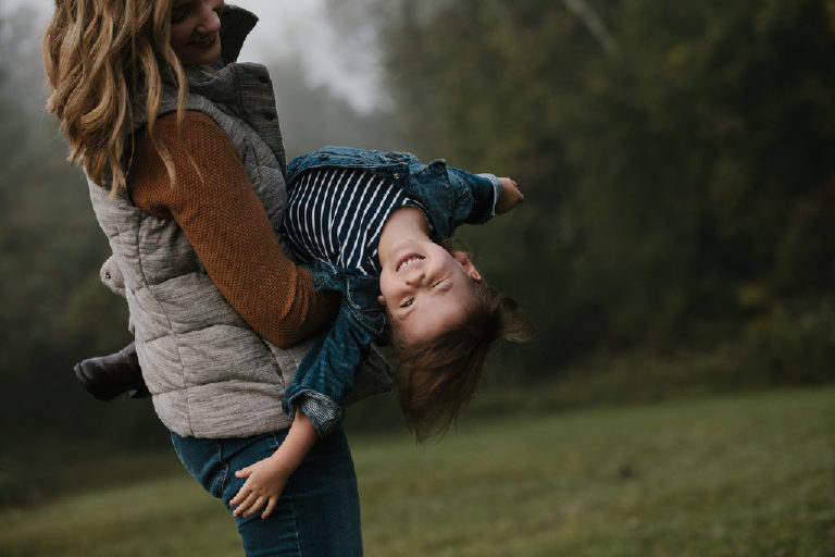 mother spinning daughter in foggy meadow for family portrait by New Hope photographer Kasey Ivan