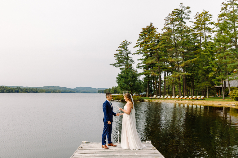Bride and groom stand on the end of the dock reciting their private vows just before their wedding ceremony at the Tarry A While Resort in Bridgton Maine