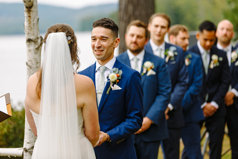 Groom holding bride's hands and smiling at the wedding ceremony at the Tarry A While Resort in Bridgton Maine