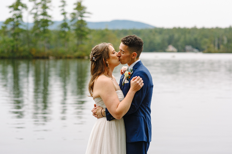 Bride and groom couple kissing next to the lake on their wedding day at the Tarry A While Resort in Bridgton Maine