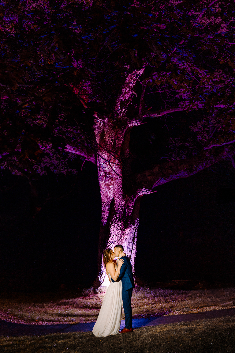 Couple kiss at nighttime under a purple tree at the Tarry A While Resort in Bridgton Maine by wedding photographer Kasey Ivan Photography